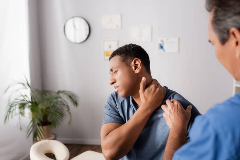 Man showing doctor where his neck pain is