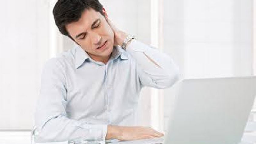 Man experiencing neck pain while working on a laptop