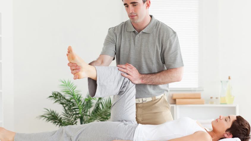 Chiropractor conducting a therapeutic leg stretch for injury recovery.