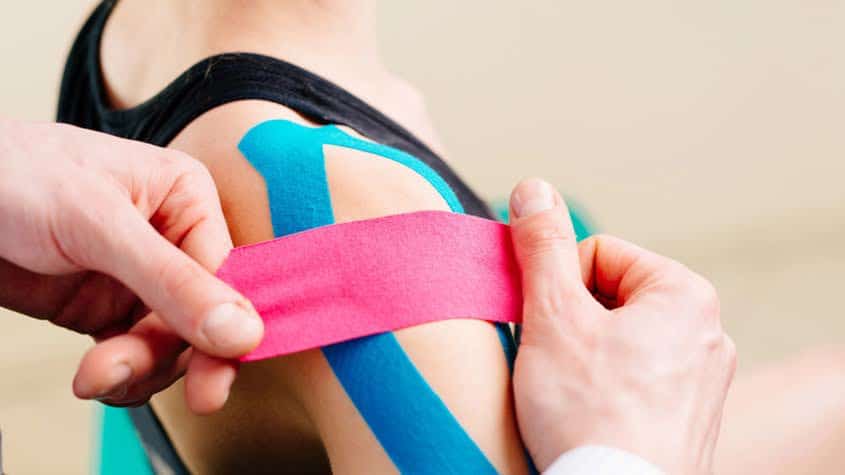 Chiropractor using kinesiology tape to support shoulder muscles in injury recovery