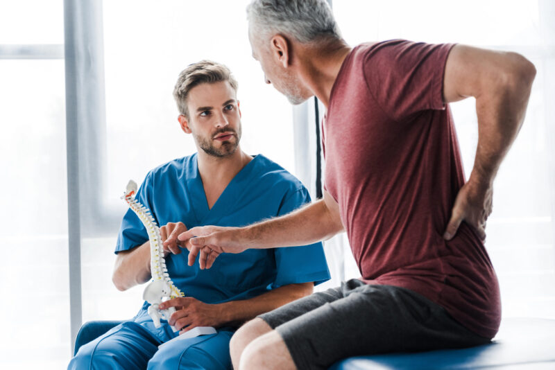 Man with low back pain pointing at spine